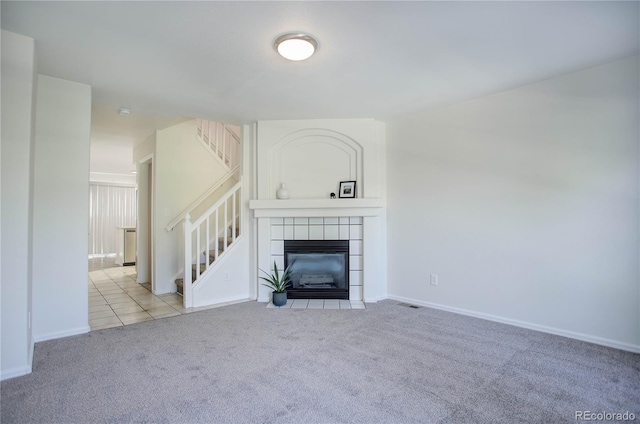 unfurnished living room featuring a tile fireplace and light colored carpet