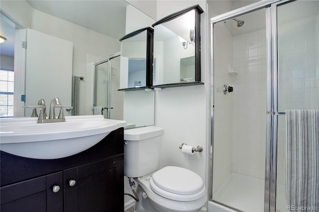 bathroom with vanity, toilet, and a shower with door