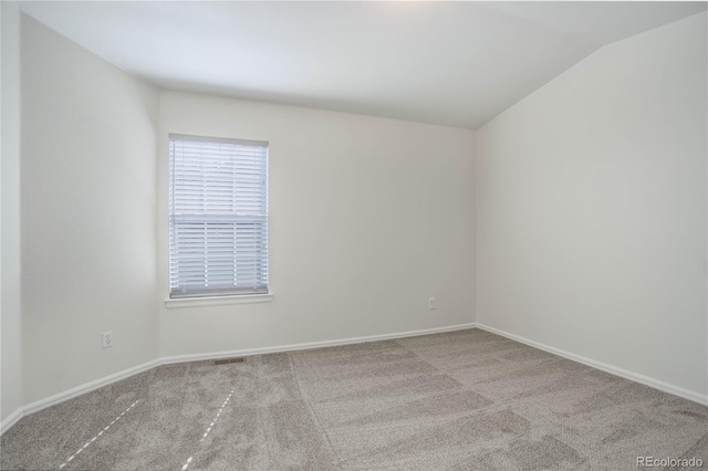 carpeted spare room featuring vaulted ceiling