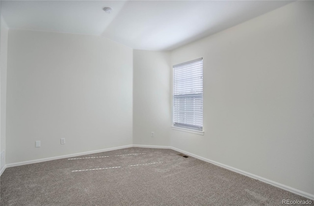 spare room featuring carpet floors and vaulted ceiling