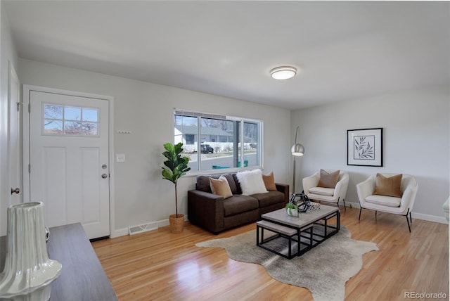 living area featuring baseboards, visible vents, and light wood finished floors