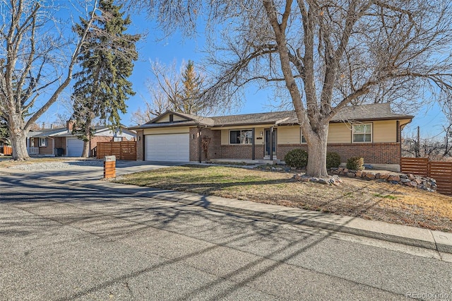 ranch-style home with concrete driveway, brick siding, fence, and an attached garage