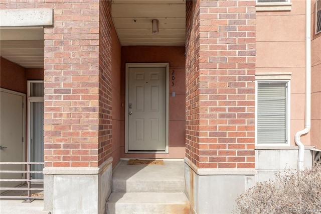 doorway to property featuring brick siding