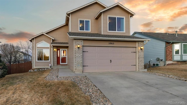 view of front facade featuring fence, a yard, concrete driveway, an attached garage, and brick siding