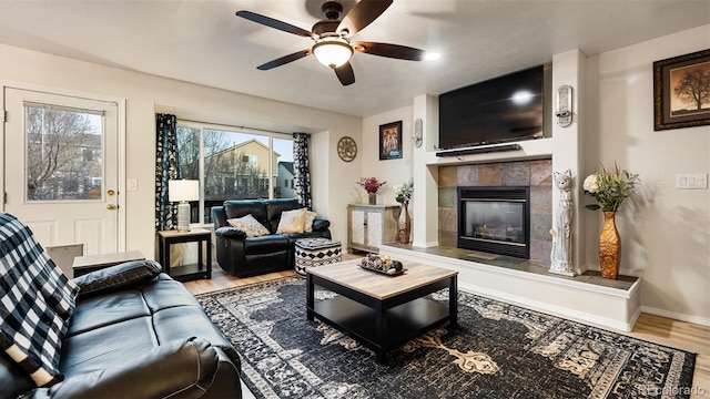 living area with wood finished floors, a ceiling fan, baseboards, and a tile fireplace