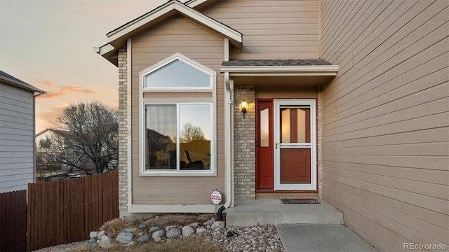 entrance to property featuring brick siding and fence