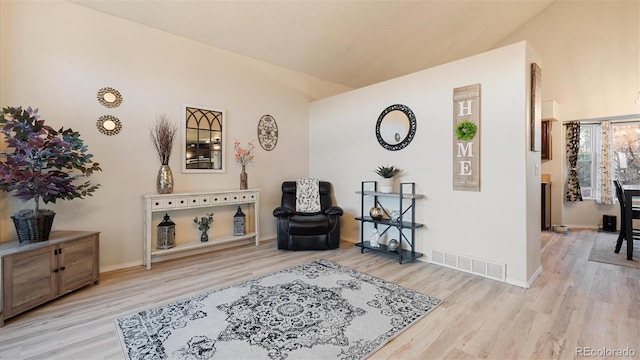 sitting room with visible vents, baseboards, wood finished floors, and vaulted ceiling