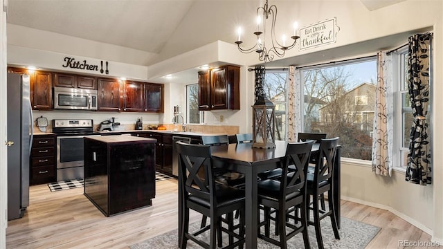 kitchen featuring light wood-style flooring, a center island, appliances with stainless steel finishes, light countertops, and a chandelier