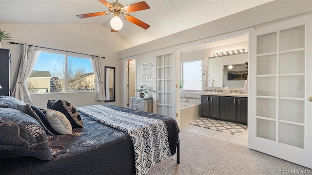 bedroom with ensuite bath, light tile patterned flooring, light colored carpet, ceiling fan, and vaulted ceiling