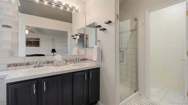 full bathroom featuring double vanity, a shower stall, a ceiling fan, and a sink