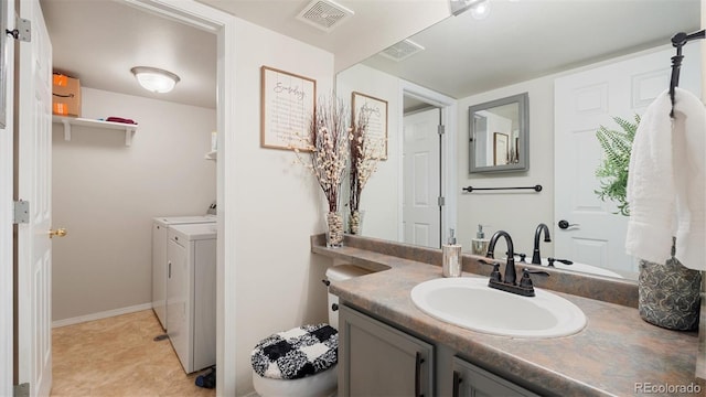 bathroom with vanity, washing machine and dryer, visible vents, and baseboards