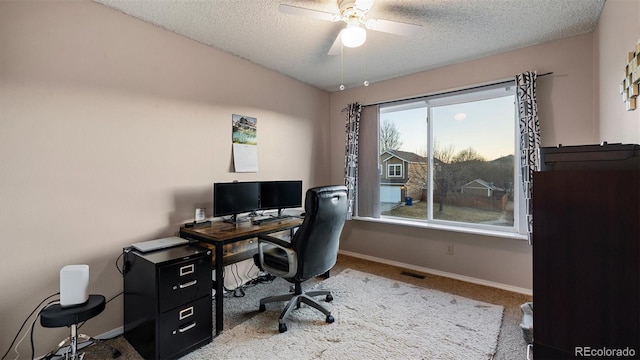 carpeted office space with a textured ceiling, baseboards, and ceiling fan