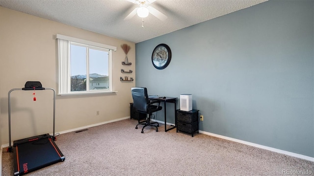 carpeted office with visible vents, baseboards, a textured ceiling, and a ceiling fan