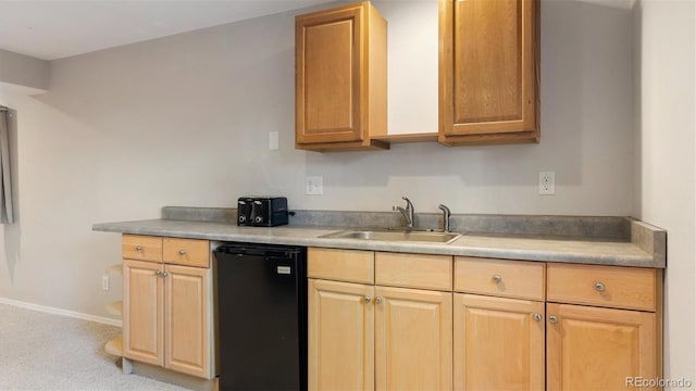 kitchen with baseboards, light countertops, black dishwasher, and a sink