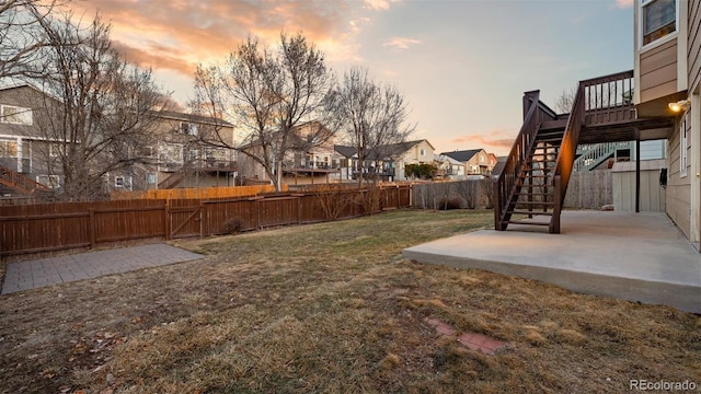 yard at dusk featuring stairs, a patio area, a fenced backyard, and a residential view