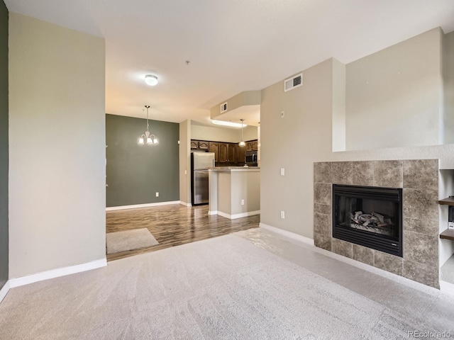 2133 Krisron Rd Unit A202, Fort Collins, CO 80525 - unfurnished living room featuring carpet, a chandelier, and a tiled fireplace