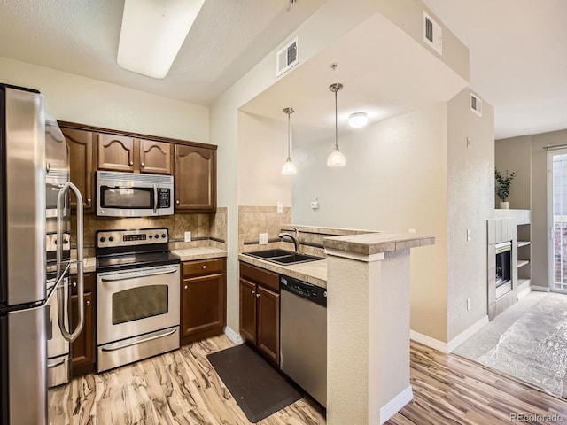 2133 Krisron Rd Unit A202, Fort Collins, CO 80525 - kitchen featuring stainless steel appliances, a peninsula, light wood-type flooring, backsplash, and a fireplace