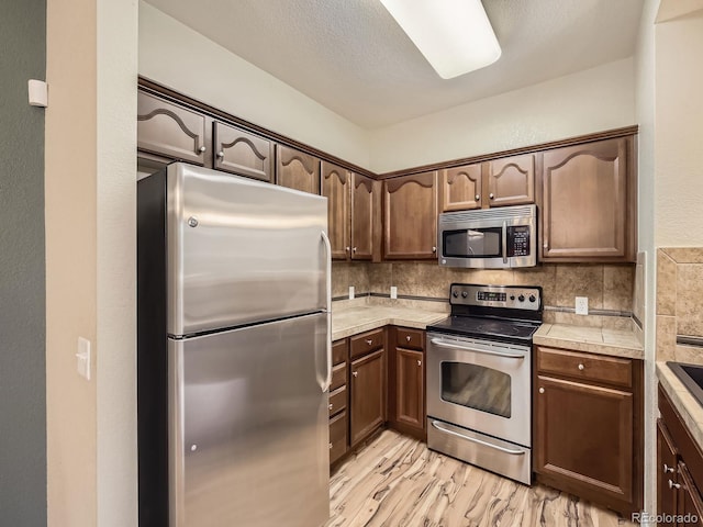 2133 Krisron Rd Unit A202, Fort Collins, CO 80525 - kitchen with stainless steel appliances, decorative backsplash, light wood-style floors, and dark brown cabinets