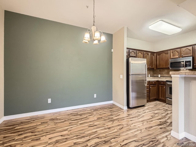 2133 Krisron Rd Unit A202, Fort Collins, CO 80525 - kitchen featuring stainless steel appliances, light wood finished floors, dark brown cabinets, a chandelier, and backsplash