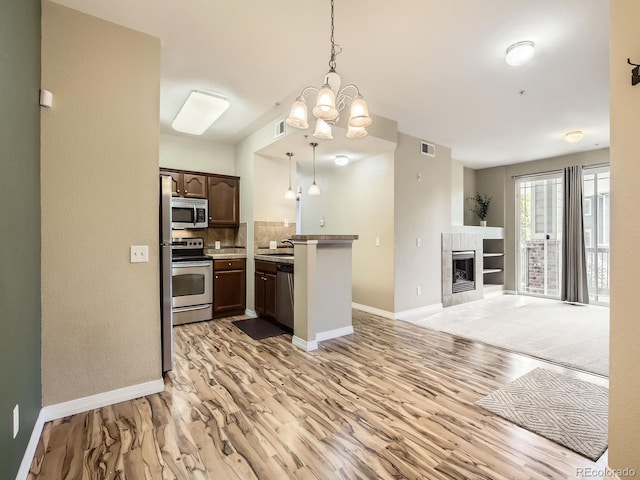 2133 Krisron Rd Unit A202, Fort Collins, CO 80525 - kitchen featuring appliances with stainless steel finishes, open floor plan, a peninsula, light wood-type flooring, and a chandelier