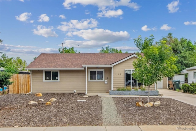 ranch-style house with a shingled roof, driveway, and fence