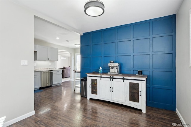 interior space featuring dark wood finished floors, arched walkways, a decorative wall, and dishwasher