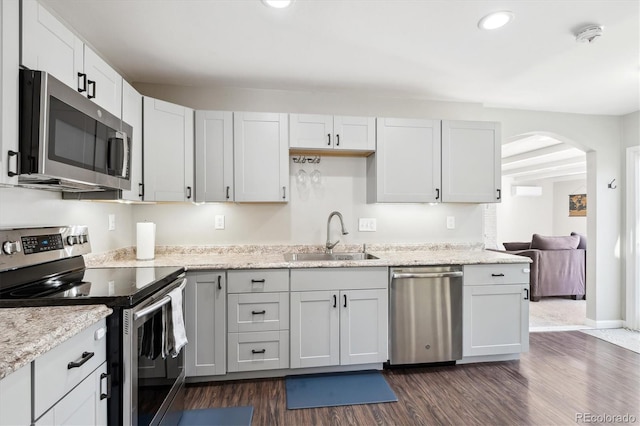 kitchen with arched walkways, recessed lighting, stainless steel appliances, a sink, and dark wood-style floors