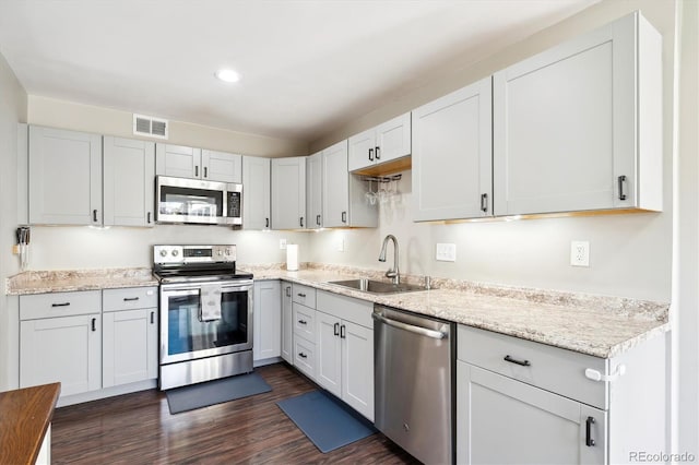 kitchen featuring dark wood-style flooring, visible vents, appliances with stainless steel finishes, white cabinets, and a sink