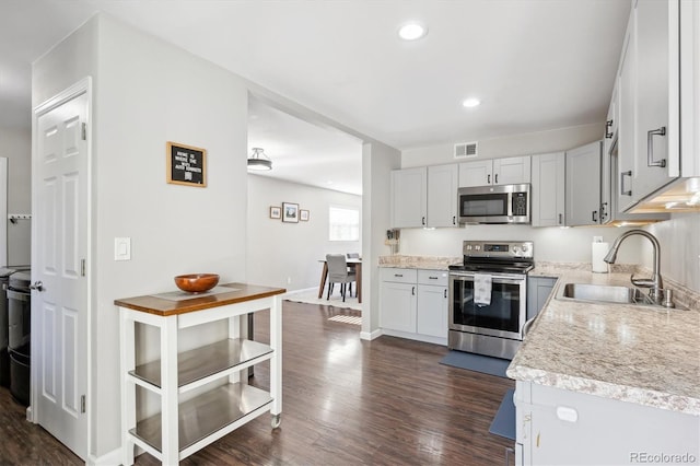 kitchen featuring light countertops, visible vents, appliances with stainless steel finishes, dark wood-type flooring, and a sink