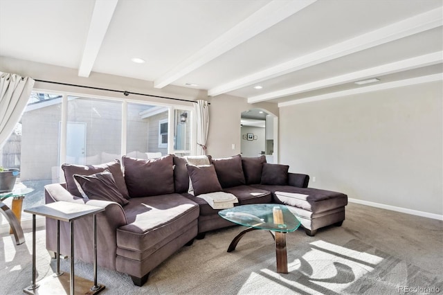 living room featuring arched walkways, beam ceiling, a wealth of natural light, light carpet, and baseboards