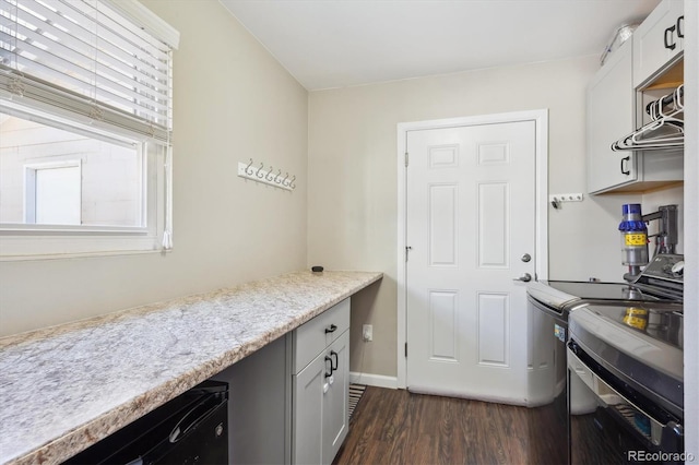 clothes washing area with dark wood-style floors, baseboards, cabinet space, and washing machine and clothes dryer