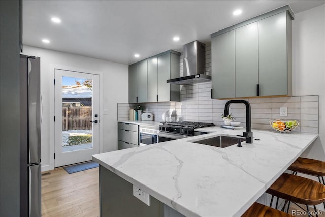 kitchen with a kitchen breakfast bar, kitchen peninsula, wall chimney exhaust hood, and gray cabinetry