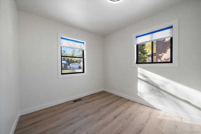 spare room featuring light hardwood / wood-style floors and a healthy amount of sunlight