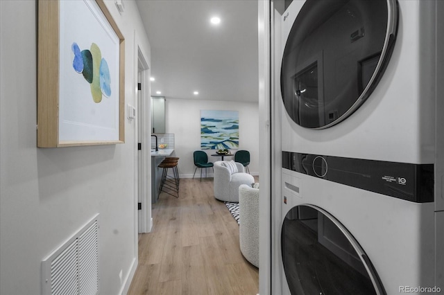 washroom with light wood-type flooring and stacked washer and clothes dryer