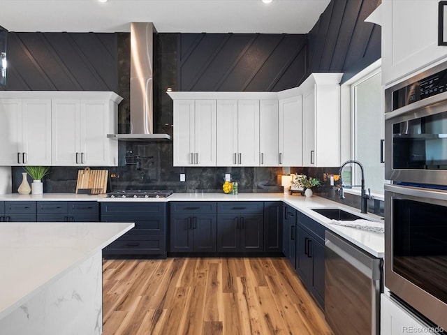 62101 E 32nd Ct, Strasburg, CO 80136 - kitchen with a sink, appliances with stainless steel finishes, wall chimney exhaust hood, light wood-style flooring, and tasteful backsplash