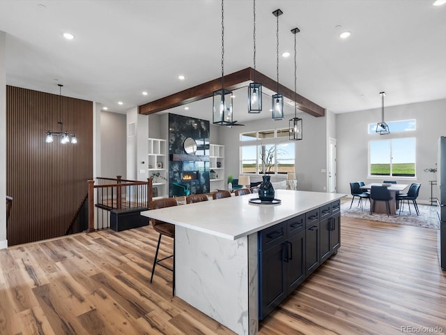 62101 E 32nd Ct, Strasburg, CO 80136 - kitchen with light wood-style flooring, light countertops, open floor plan, a kitchen island, and healthy amount of natural light