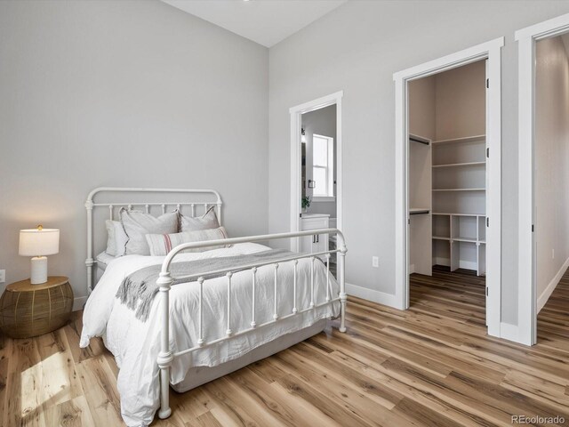 62101 E 32nd Ct, Strasburg, CO 80136 - bedroom featuring wood finished floors, a spacious closet, baseboards, and a closet