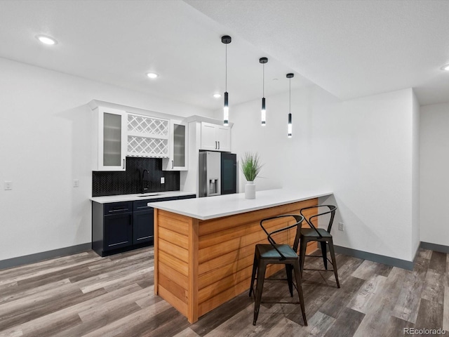 62101 E 32nd Ct, Strasburg, CO 80136 - kitchen with stainless steel refrigerator with ice dispenser, a sink, wood finished floors, glass insert cabinets, and a peninsula