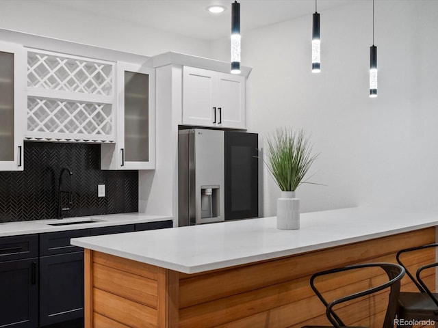62101 E 32nd Ct, Strasburg, CO 80136 - kitchen with stainless steel fridge, a sink, light countertops, tasteful backsplash, and hanging light fixtures