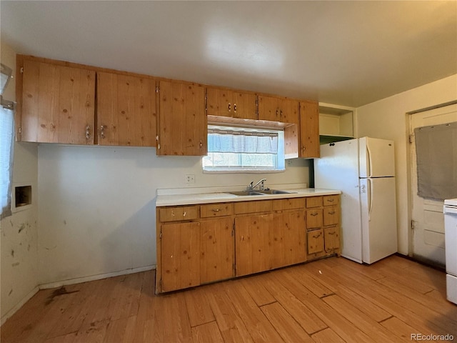 kitchen featuring light countertops, light wood-style floors, freestanding refrigerator, and a sink