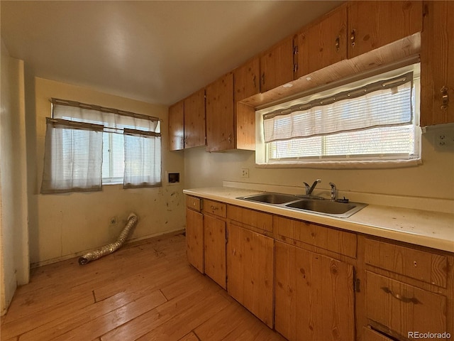 kitchen with a sink, brown cabinets, light wood-style floors, and light countertops