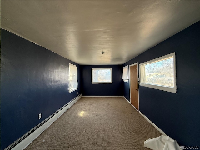 empty room featuring baseboards, baseboard heating, and carpet flooring