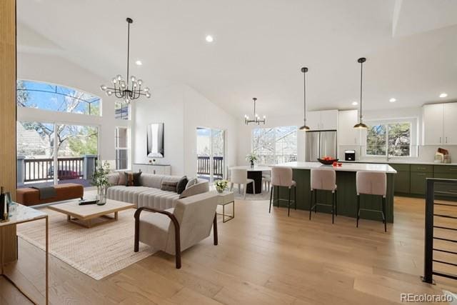 living room featuring high vaulted ceiling, a chandelier, and light hardwood / wood-style flooring