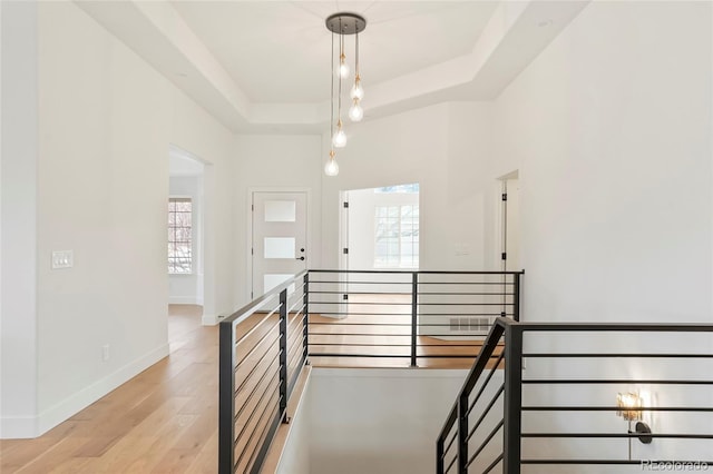 stairway with a raised ceiling, hardwood / wood-style floors, and a high ceiling