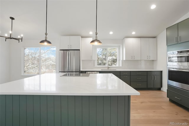 kitchen with white cabinetry, hanging light fixtures, stainless steel appliances, and a center island