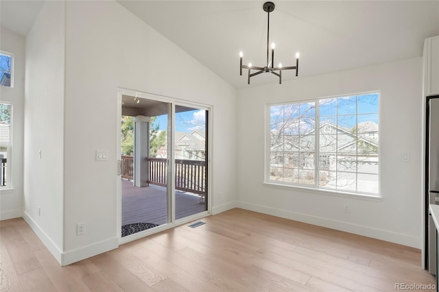 unfurnished dining area with high vaulted ceiling, a chandelier, and light wood-type flooring