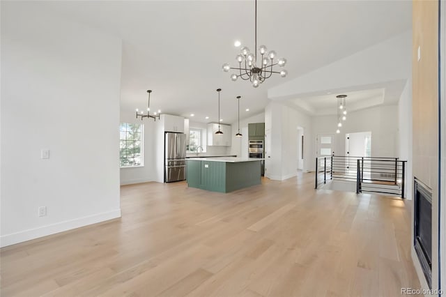 kitchen with light hardwood / wood-style flooring, stainless steel refrigerator, a center island, decorative light fixtures, and a chandelier