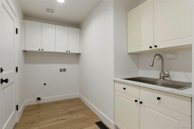 laundry room with sink, cabinets, washer hookup, light hardwood / wood-style floors, and hookup for an electric dryer