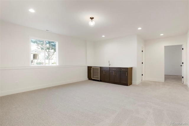 carpeted spare room featuring wine cooler and indoor bar