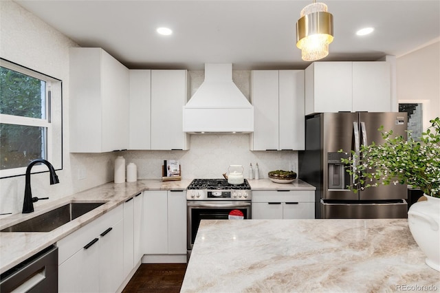 kitchen with stainless steel appliances, white cabinetry, custom range hood, and sink